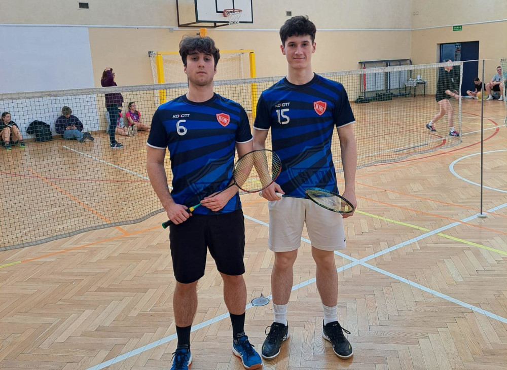 Dwóch uczniów w strojach sportowych w sali gimnastycznej trzymający rakiety do badmintona 