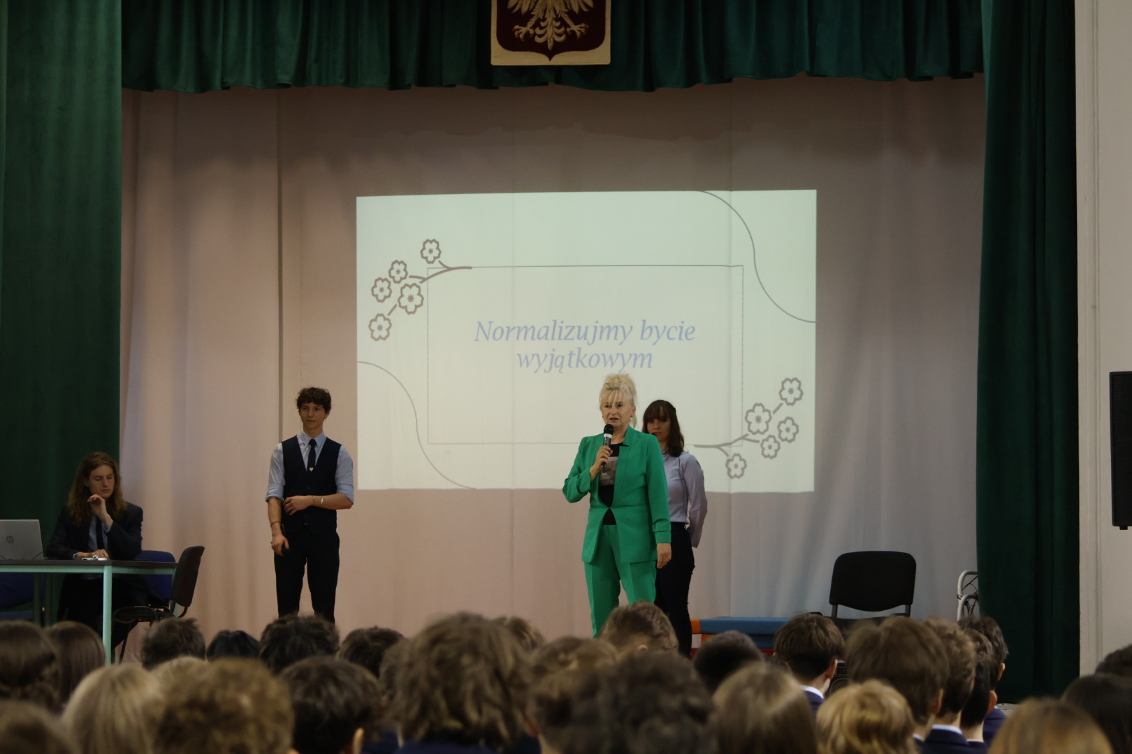 scena w auli, prowadzący, p. pedagog wita zebranych na spotkaniu