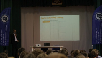 Prelegent na scenie, w tle na ekranie prezentacja