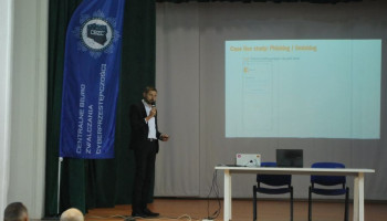 Prelegent na scenie, w tle na ekranie prezentacja