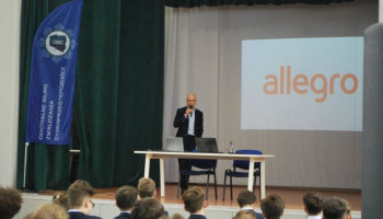 Prelegent na scenie, w tle na ekranie prezentacja