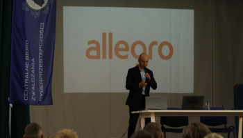 Prelegent na scenie, w tle na ekranie prezentacja z napisem Allegro