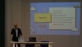 Prelegent na scenie, w tle na ekranie prezentacja