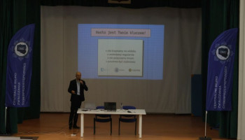 Prelegent na scenie, w tle na ekranie prezentacja