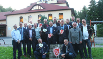 Zdjęcie grupowe uczestników spotkania przed hotelem, niektórzy trzymają „plakietki” z napisem Vb, 1985-2020 lub tarcze