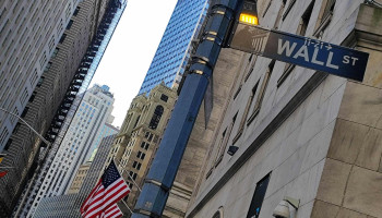 Znak drogowy, ulica Wall Street, w tle flagi amerykańskie, wieżowce