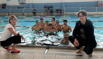 Sztafeta pływacka Śl.TZN, zdobywcy 1 miejsca z medalami, zanurzeni w wodzie basenu; na brzegu: z lewej opiekunka reprezentacji szkoły, z prawej zawodnik rezerwowy