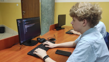 Uczeń przy komputerze, na ekranie program kod programu