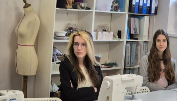 Dwie uczennice podczas prelekcji; widoczna także maszyna do szycia