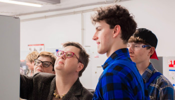 panie minister i poseł zapoznają się z instrukcją obrabiarki CNC, po prawej 2 uczniów