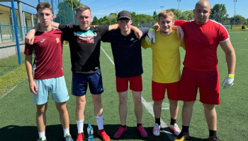 drużyna 3CFN – 5 zawodników w kolorowych strojach sportowych, w pozycji stojącej ze splecionymi rękoma na barkach kolegów; na boisku