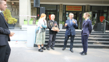 konkurs o bebokach, przed schodami, nauczyciel zadaje pytanie uczennicy, para w strojach śląskich z lewej, uczeń w górniczym stroju z koszykiem słodyczy